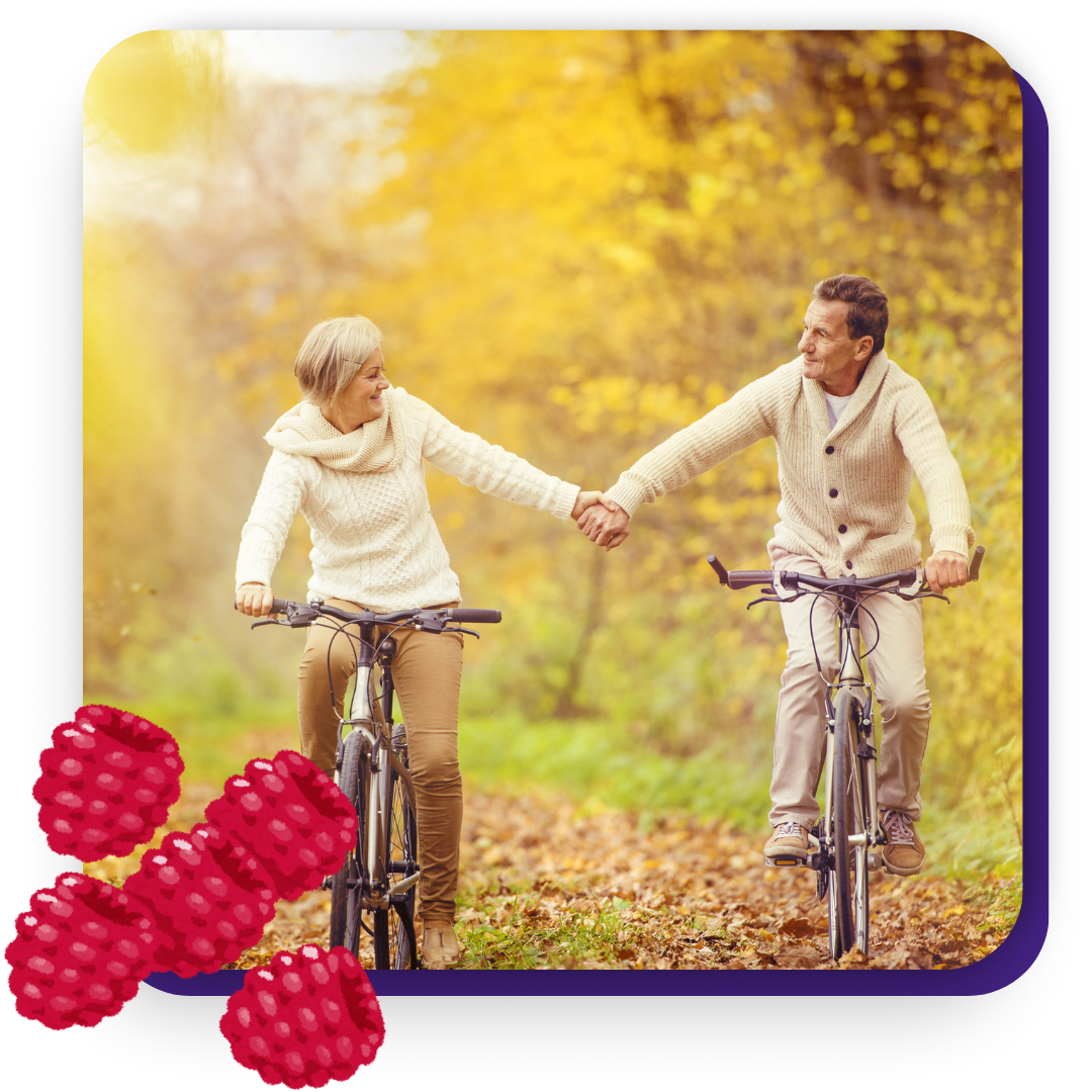 couple holding hands while riding separate bikes on a path covered in fall leaves
